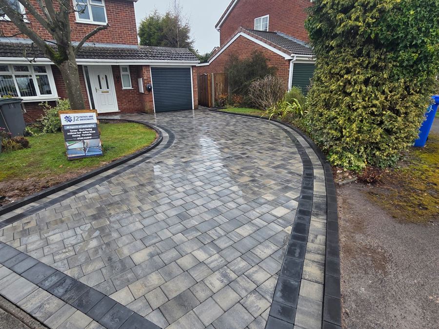 A curved block paved driveway with a charcoal soldier course border