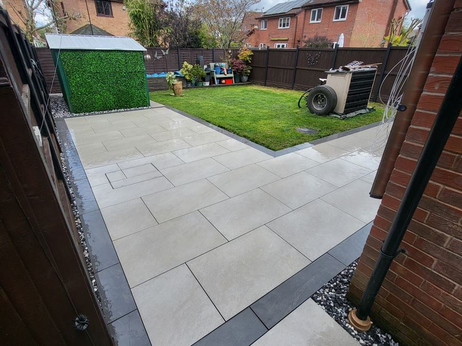 A light grey porcelain patio with a charcoal border, opening onto a lawn