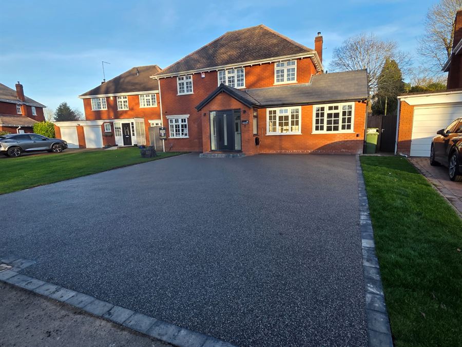 A grey resin bound driveway running the full frontage of a large detached house